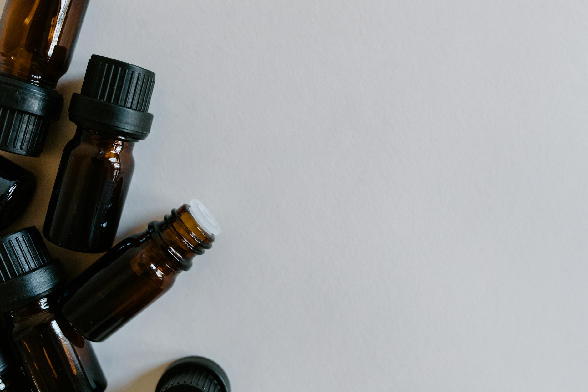 Brązowe buteleczki z olejkami eterycznymi na białym tle