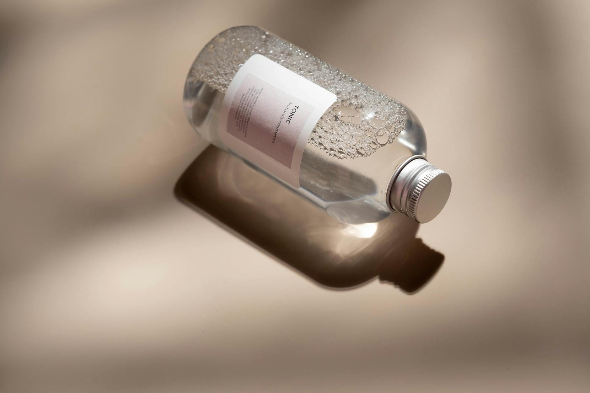 Przezroczysta butelka toniku do twarzy na lśniącej powierzchni