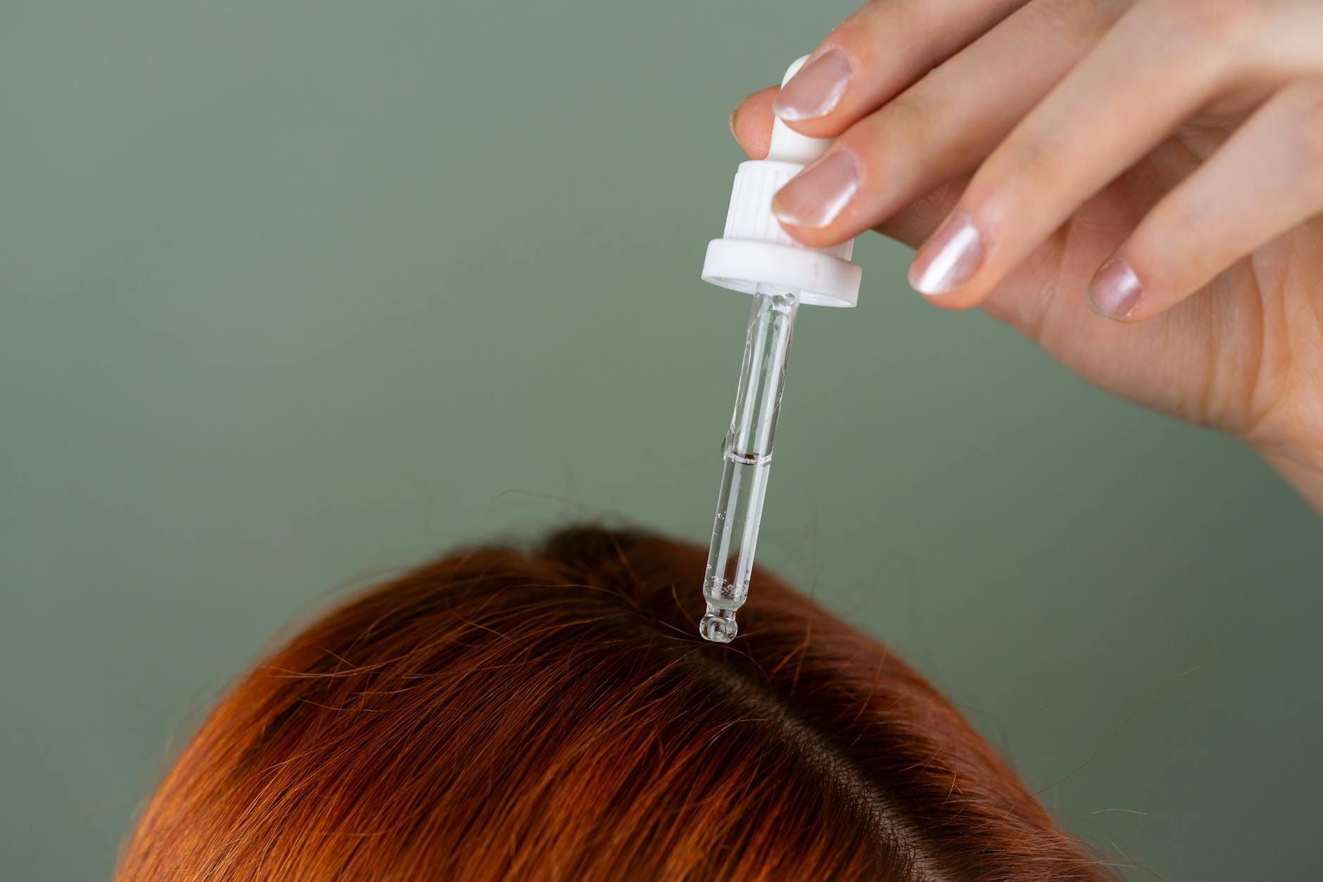 Aplikacja serum pipetą na skórę głowy przy rudych włosach