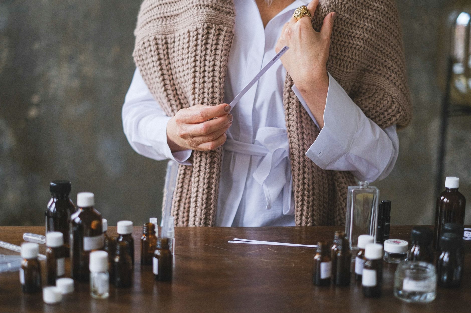 Kobieta testuje naturalne perfumy na blotterach przy drewnianym stole