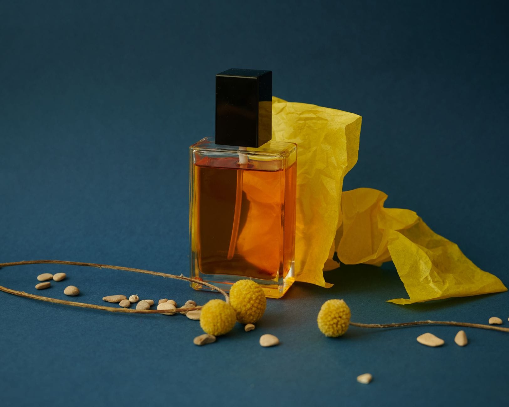 Flakon perfum na tle żółtego papieru i kwiatowych akcentów Flakon perfum na tle żółtego papieru i kwiatowych akcentów