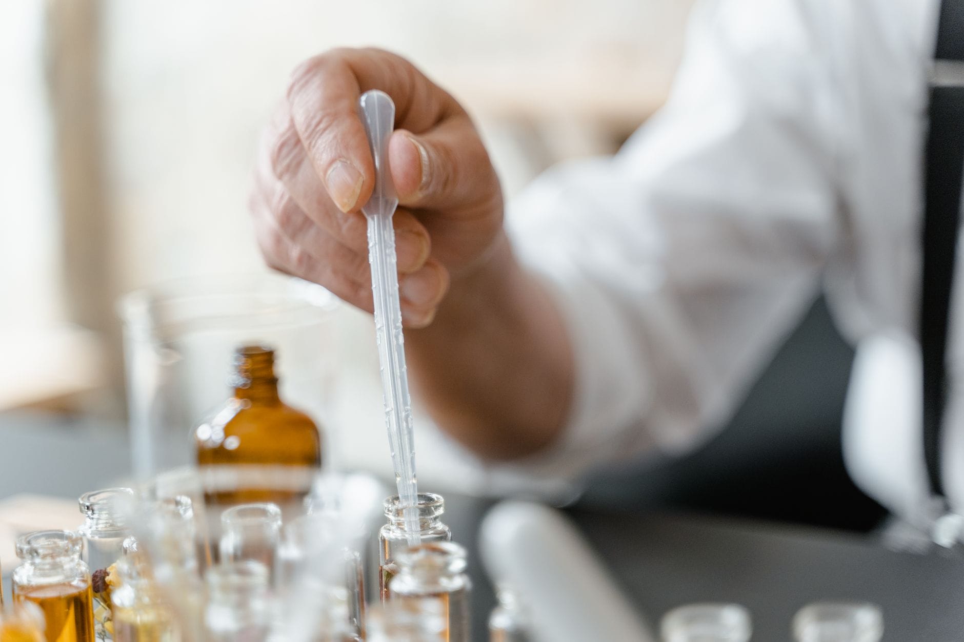 Osoba w laboratorium miesza olejki eteryczne do kompozycji zapachowej